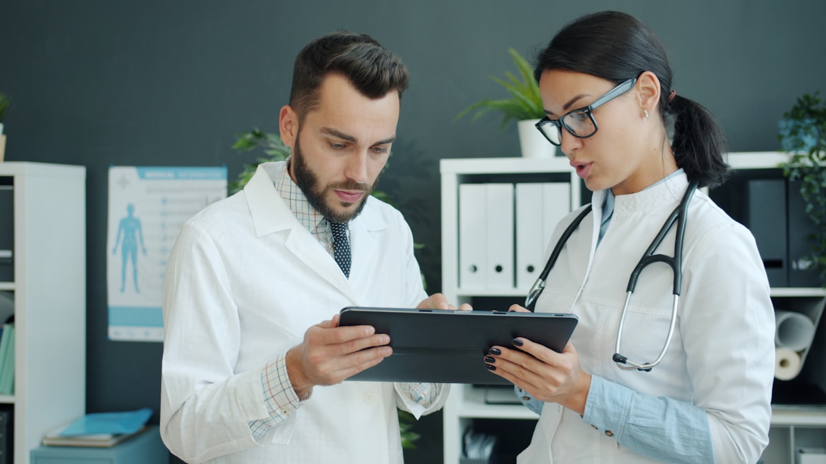Zwei Ärzte besprechen digitale Befunde auf einem Tablet