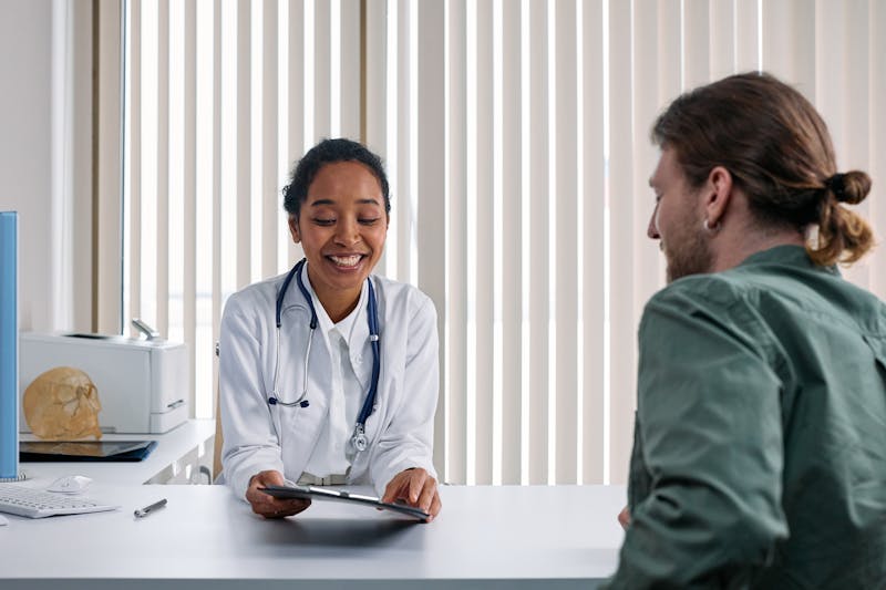 Ärztin mit digitalem Tablet im Gespräch mit Patienten